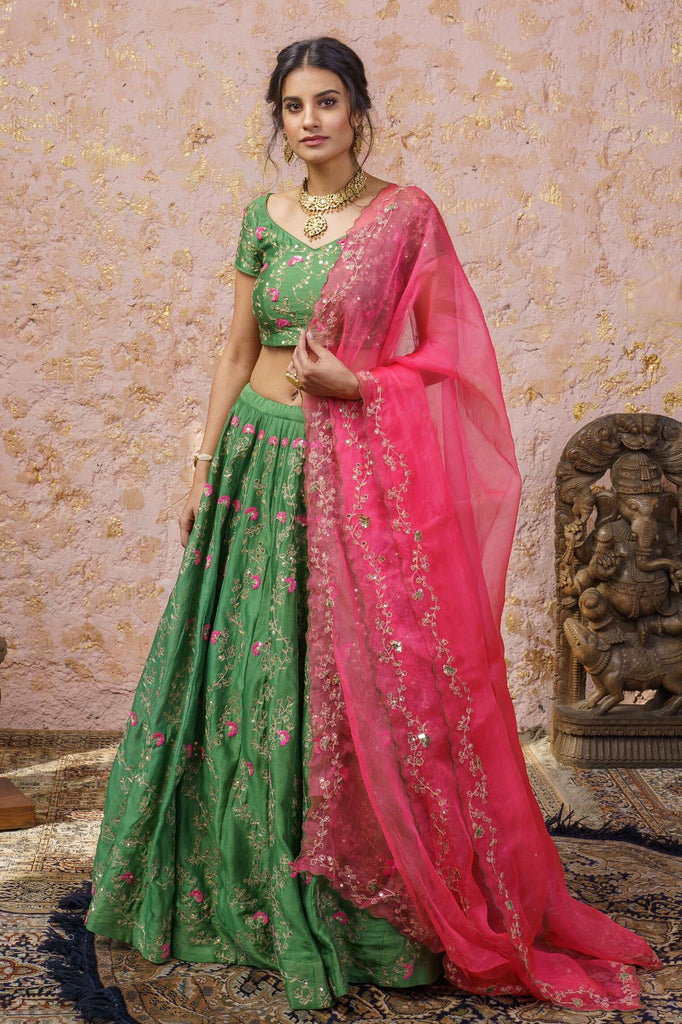 Photo of Emerald green lehenga with red tassels and contrasting dupatta